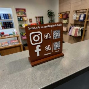 NFC stojan s QR kódmi na Instagram a Facebook umiestnený na predajnom pulte v prevádzke.